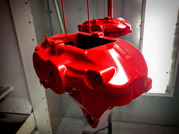 Close-up of a high-performance brake caliper with custom brake caliper powder coating in metallic red finish